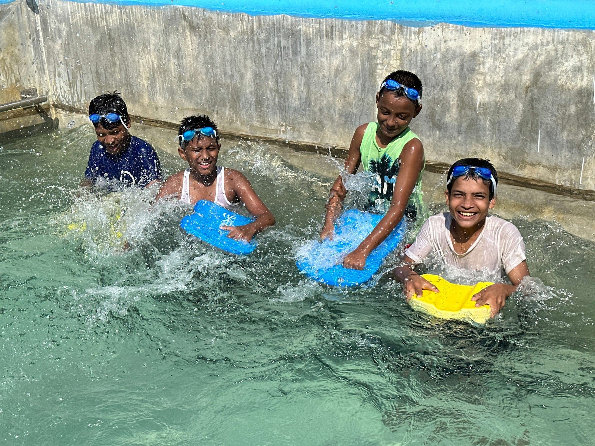 Children learning to swim with kickboards